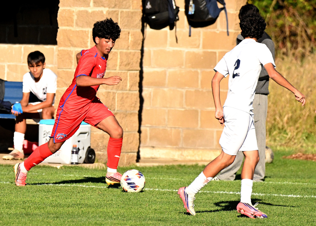 a soccer player in red dribbling