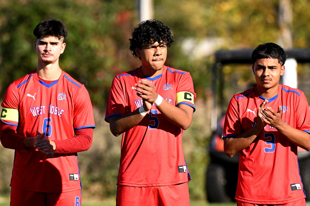 three soccer players in red clapping