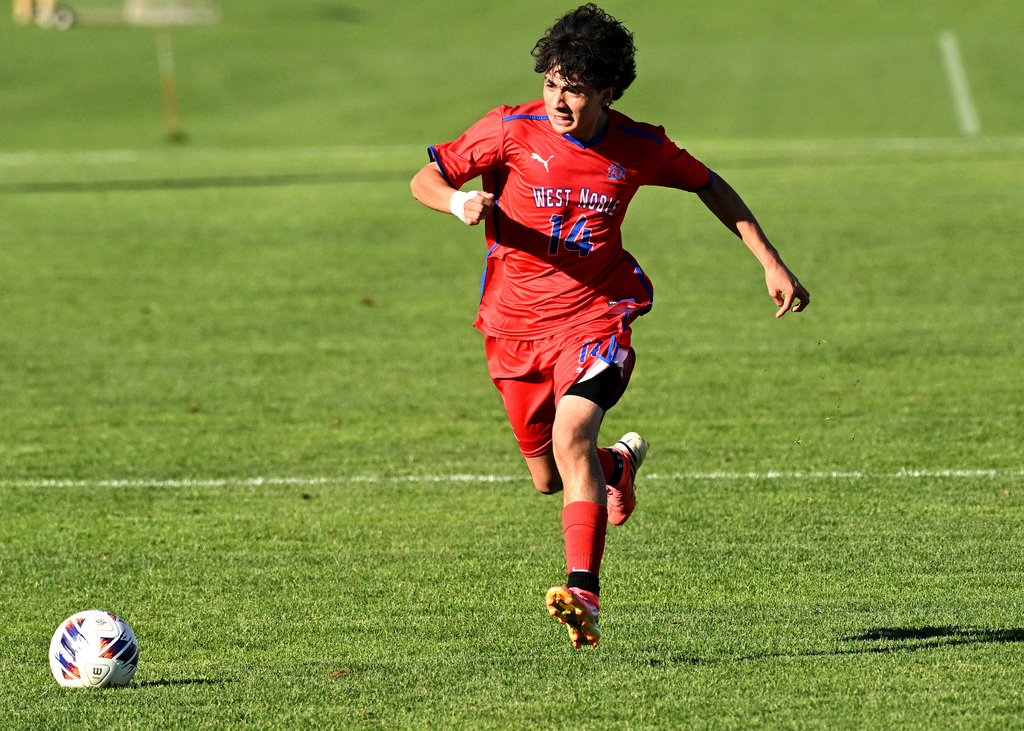 a soccer player in red dribbling the ball