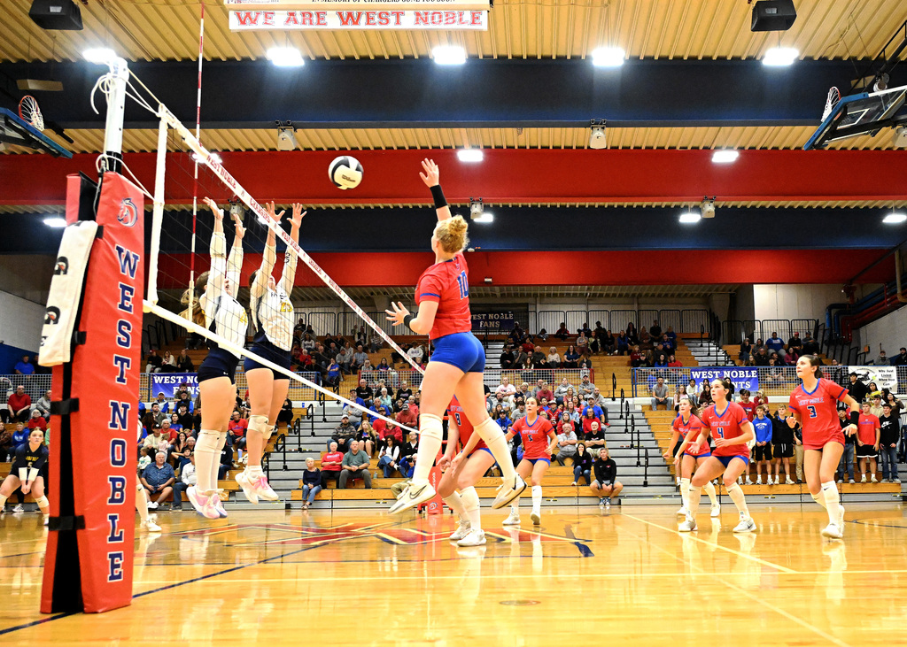 a girl in a red shirt hitting a volleyball