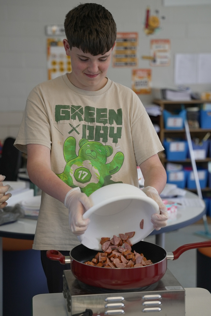 Student helping teacher make jambalaya
