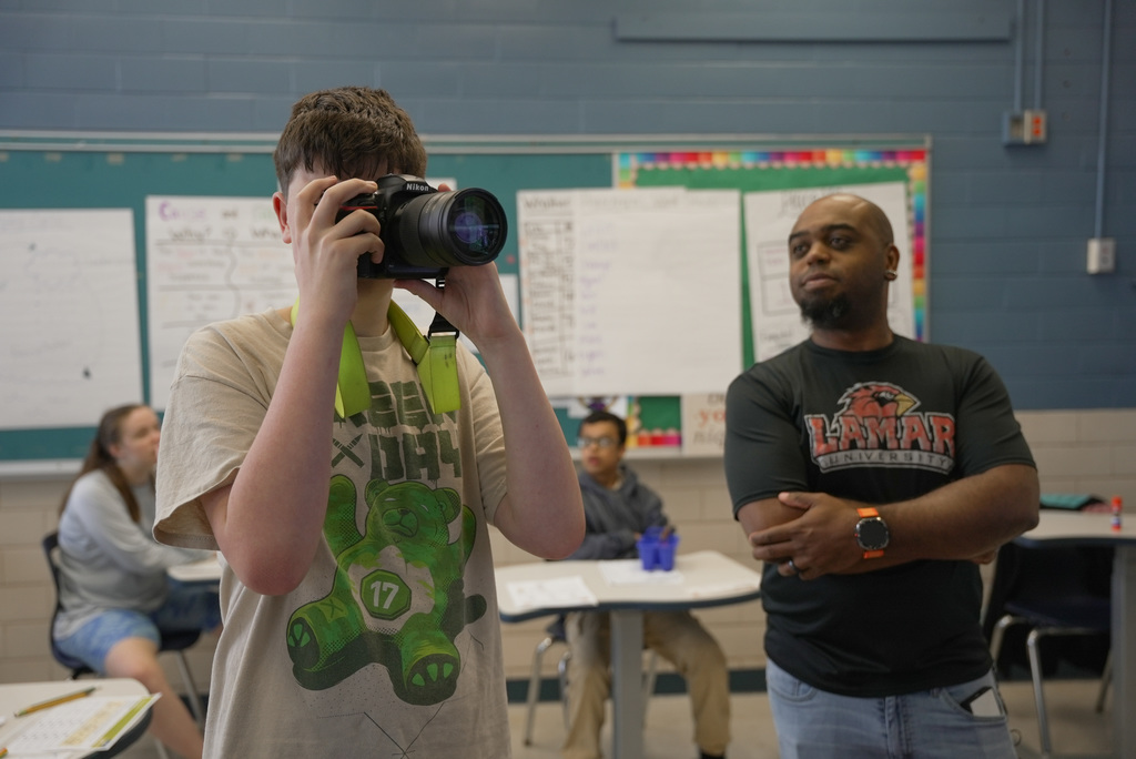 Communications Director teaching student about cameras