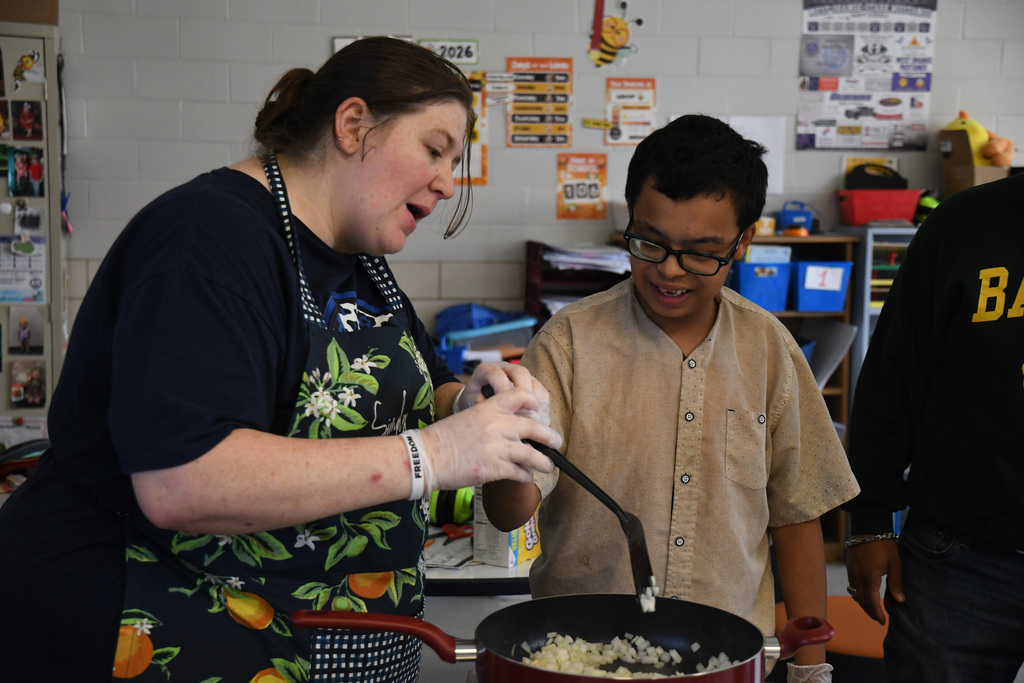 Student helping teacher make jambalaya