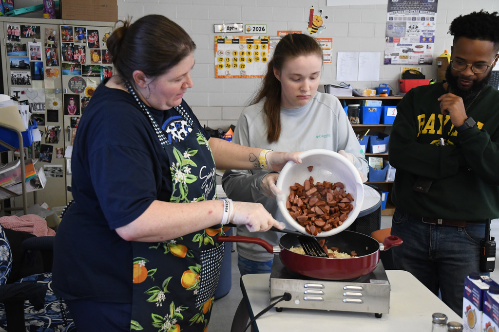 Student helping teacher make jambalaya