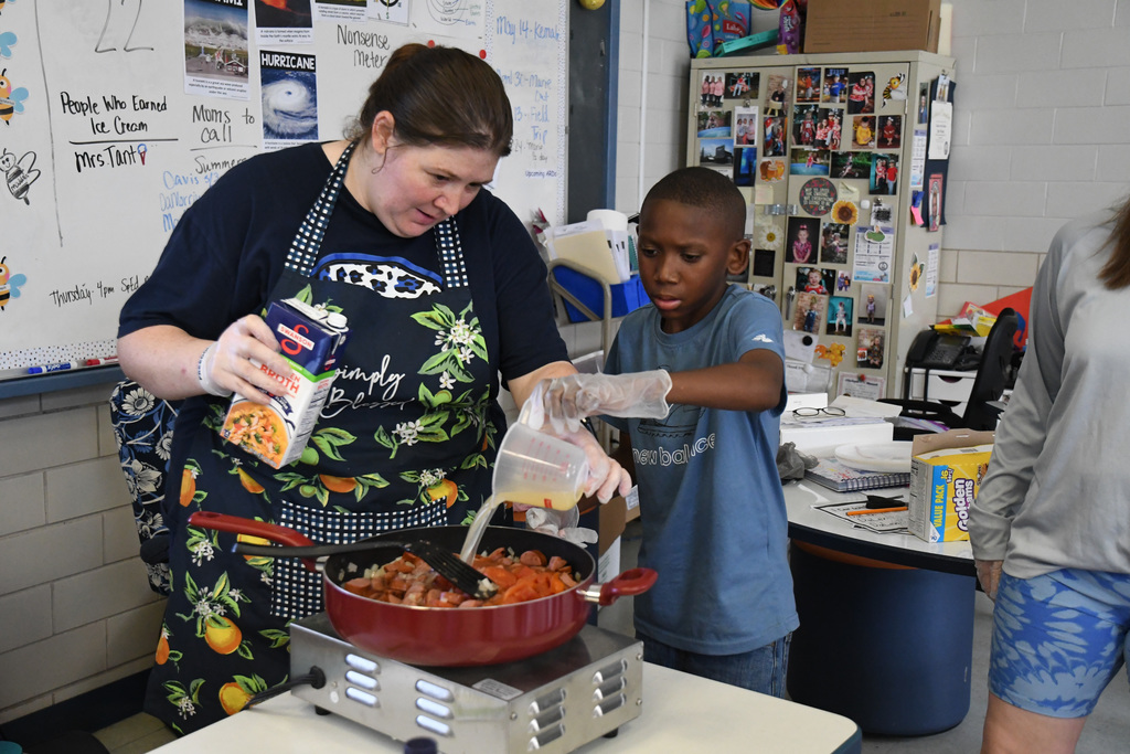 Student helping teacher make jambalaya