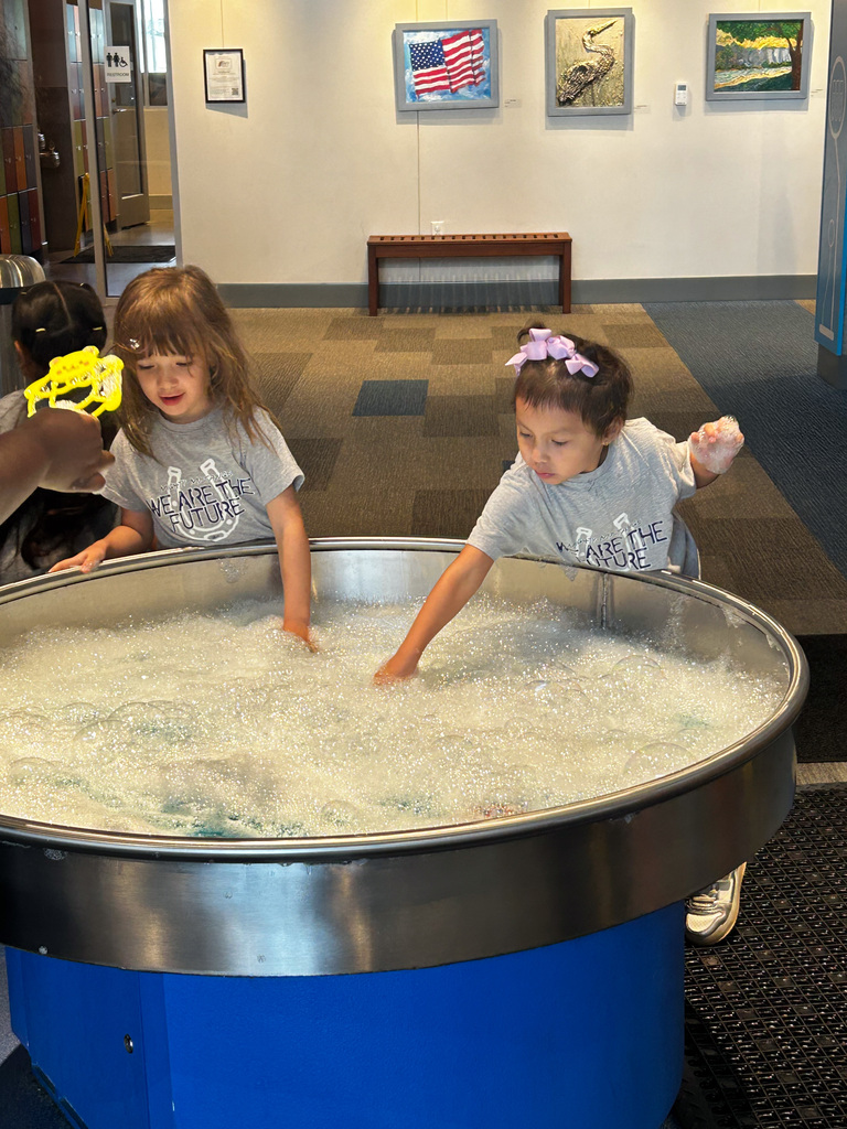 Students putting their hands in a large tub of bubbles