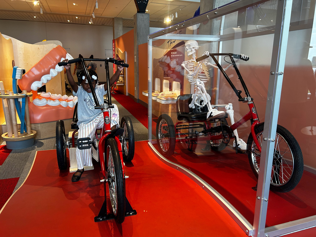 Students on a tricycle next to a skeleton on a tricycle