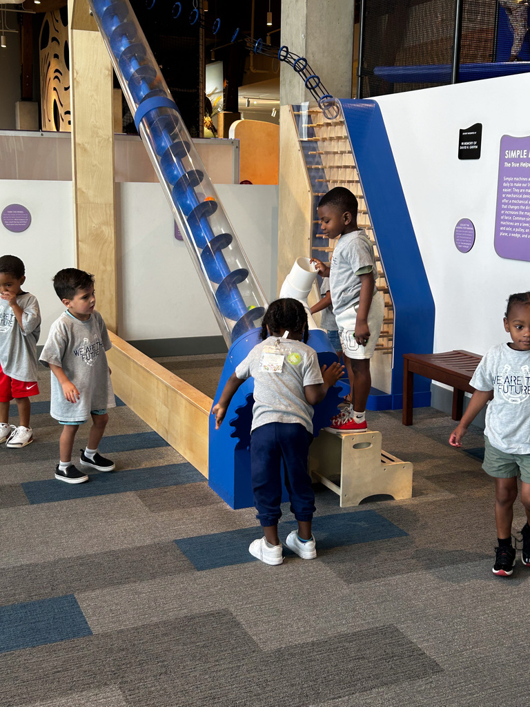 Students playing with a large screw echibit
