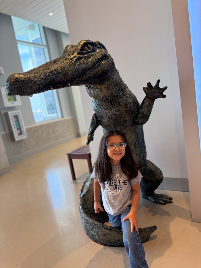 Student posing in front of a large alligator sculpture