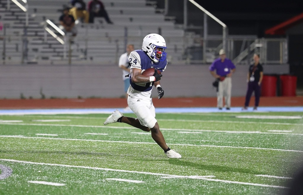 WOS Player running with a football on a field