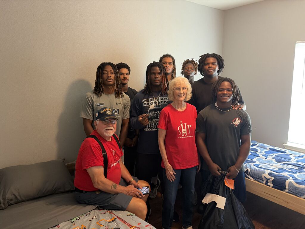 Football boys helping apartment complex set up beds