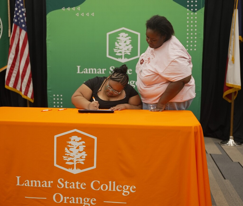 Family standing with student signing up Early College certificate