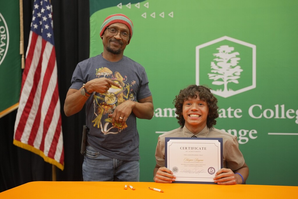 Family standing with student holding up Early College certificate