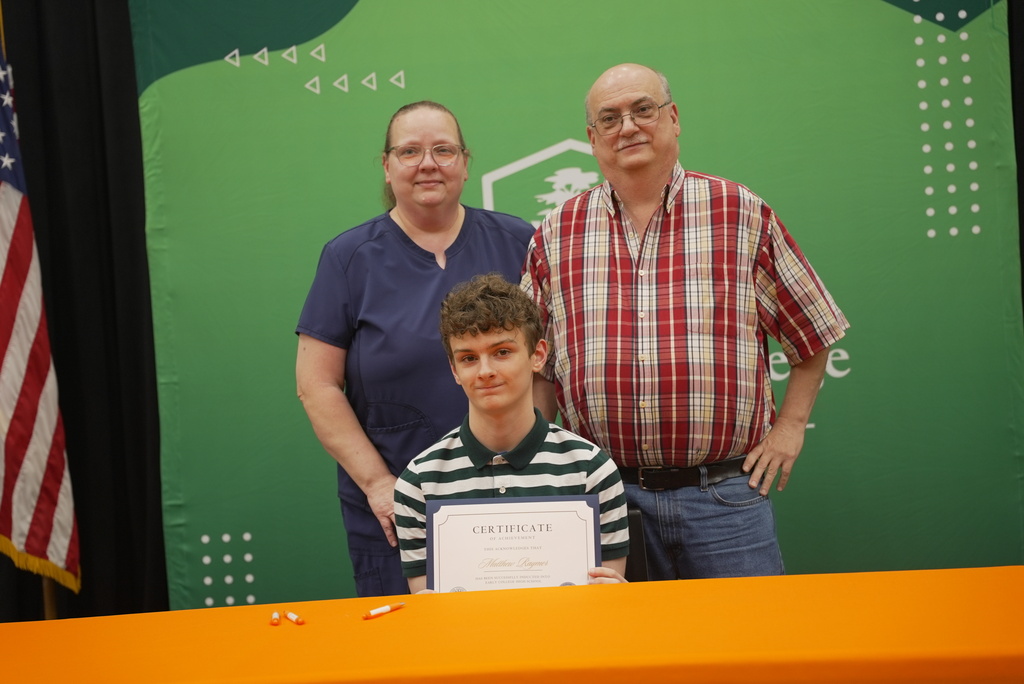 Family standing with student holding up Early College certificate