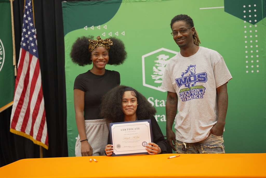 Family standing with student holding up Early College certificate