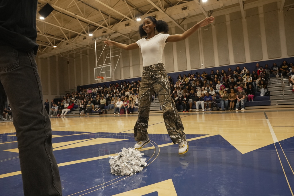 student playing a pep rally game, mid-jumping jacks