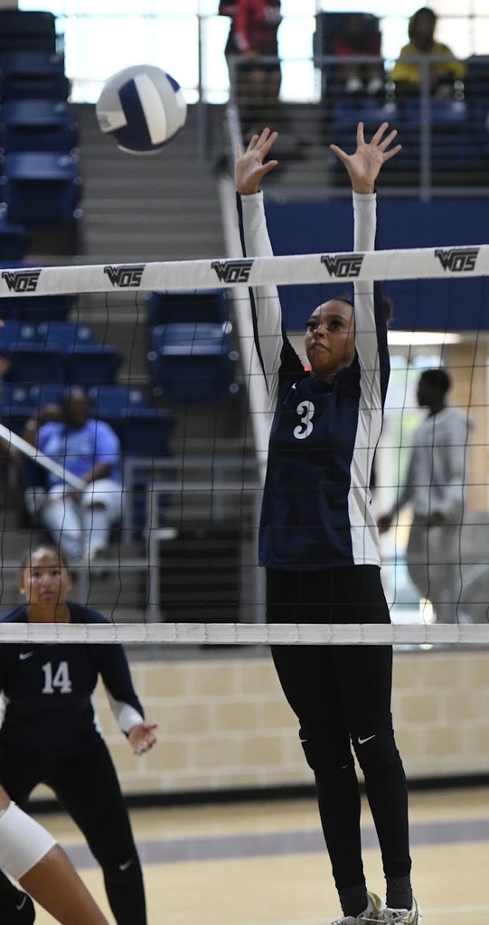 WOS volleyball player blocking ball at net