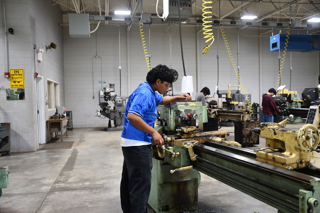Student in blue shirt resets a piece of heavy machinery
