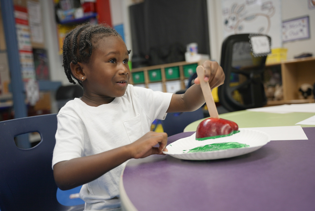 boy using an apple to make a stamp with green paint
