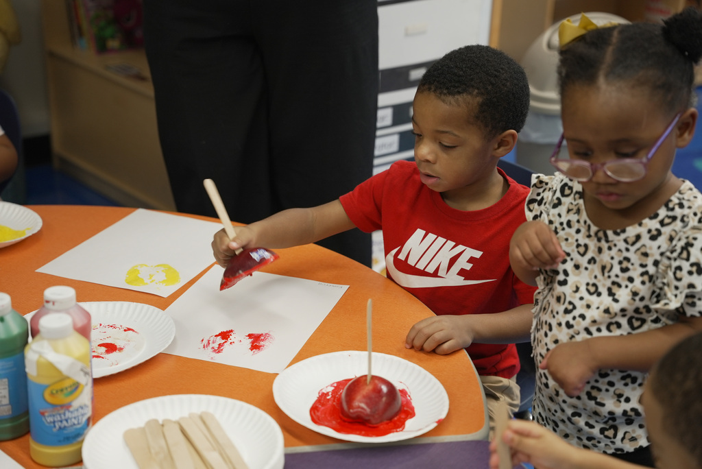 two students using apples to make colored stamps on paper
