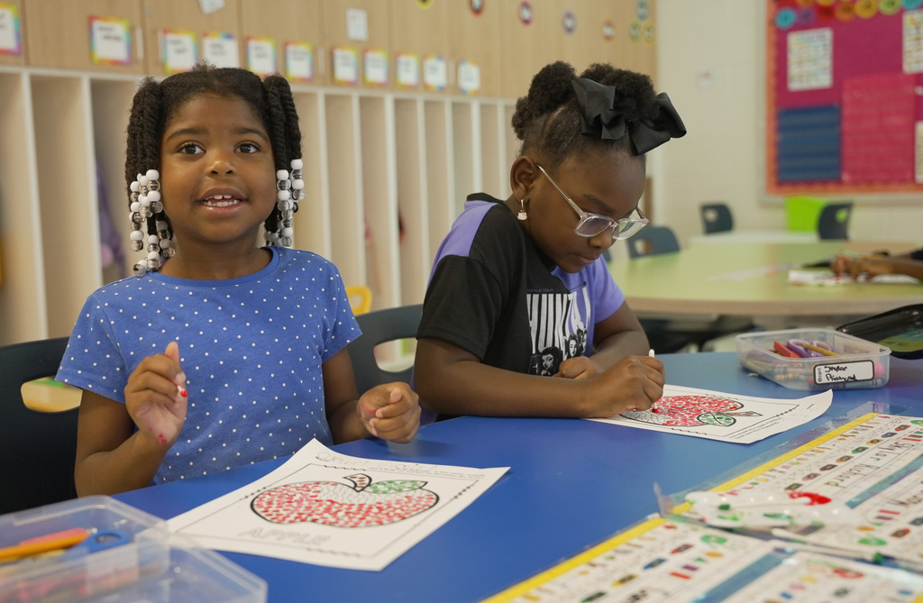 two girls coloring a fill in apple worksheet