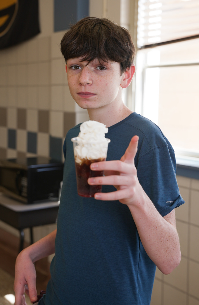 Boy holding up a dirty soda to the camera