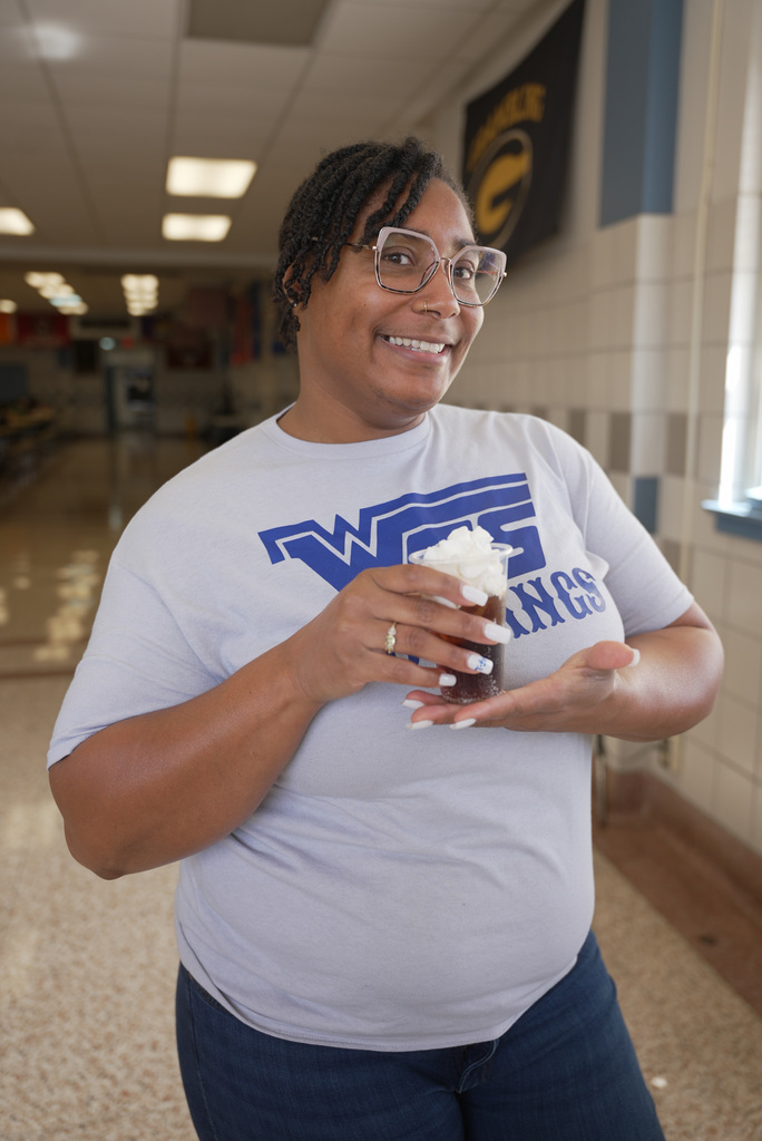 teacher smiling and holding a dirty soda