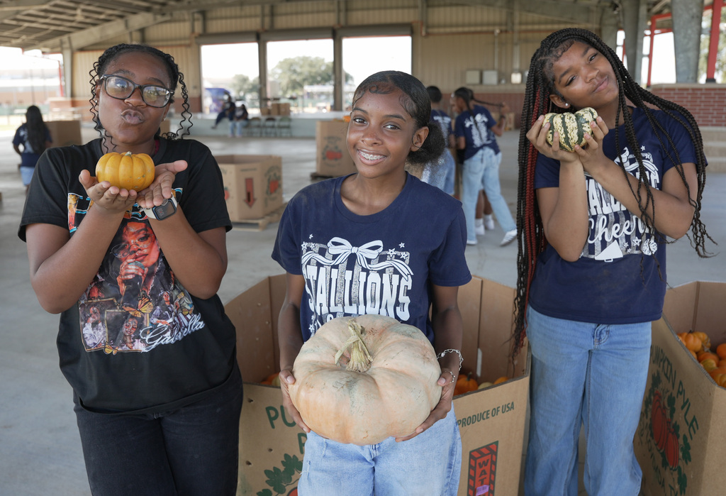 3 students posing with a variety of pumpkins