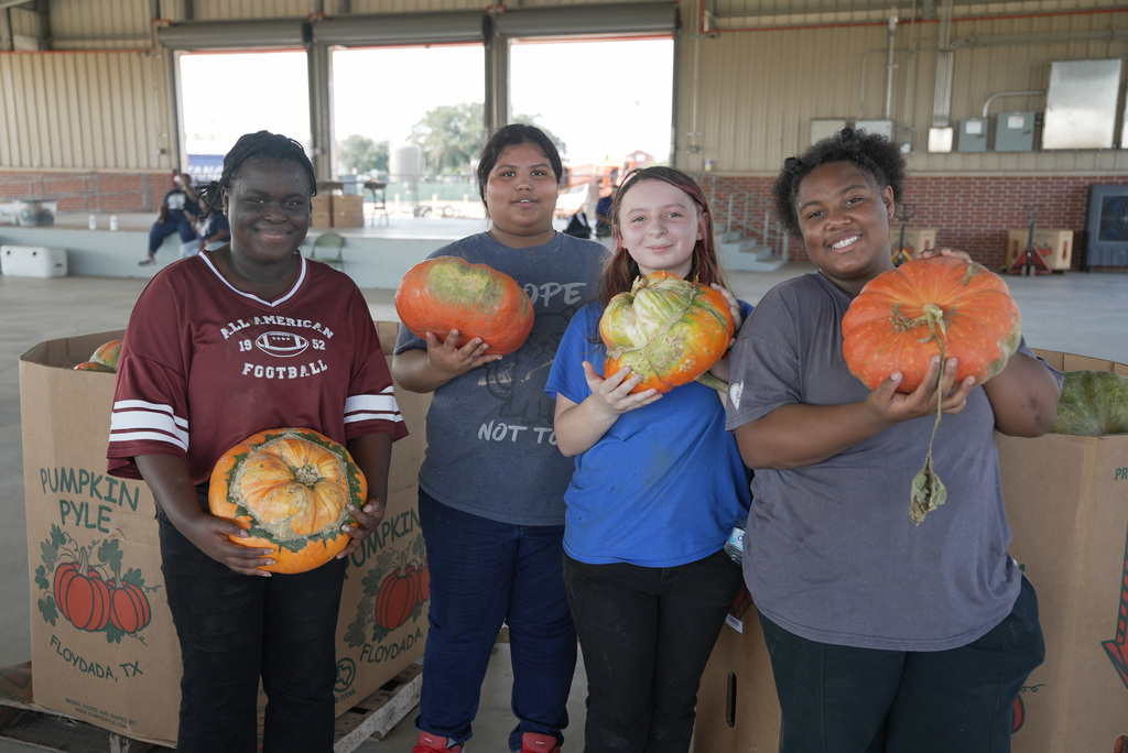 4 students holding pumpkins