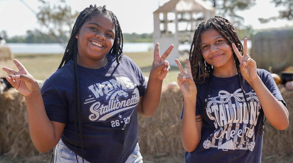 two students holding up peace signs for a photo