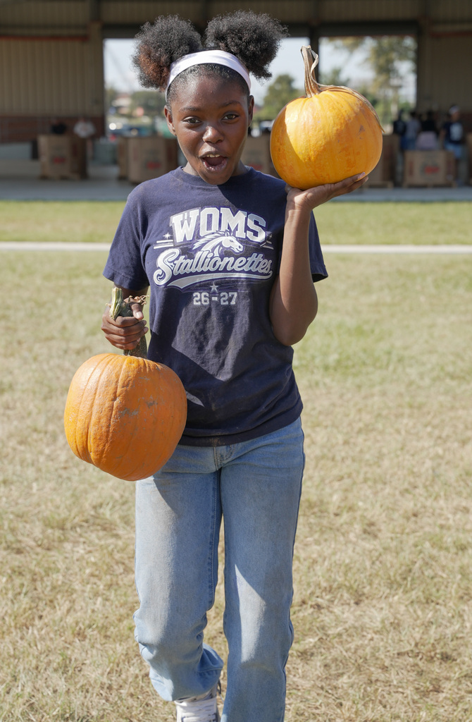 student with a shocked face carrying two pumpkins