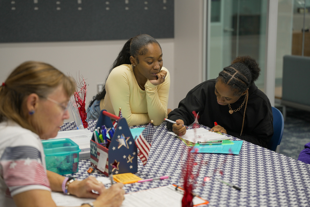 student filling out voter registration form while her friend watches