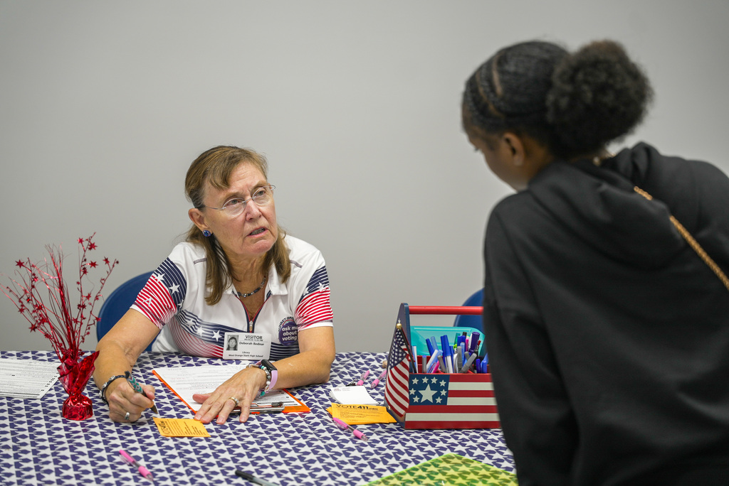 woman explaining a voter information site to a student