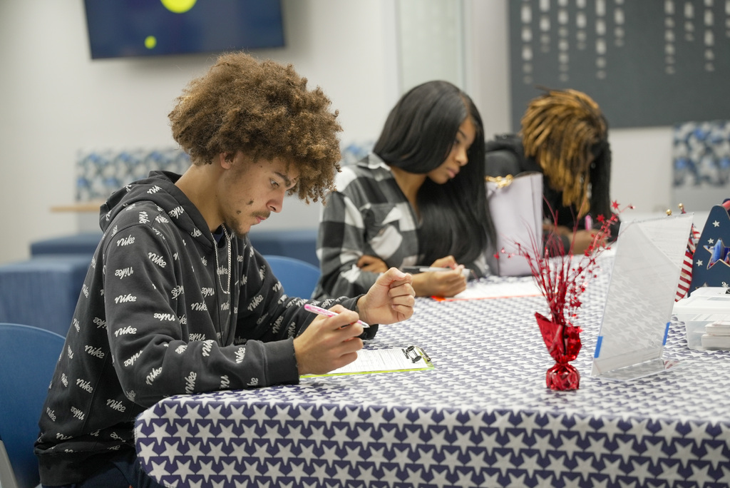 three students sitting at a table filling out vote registration forms