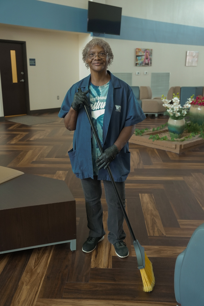 Education Service Center custodian holding a broom