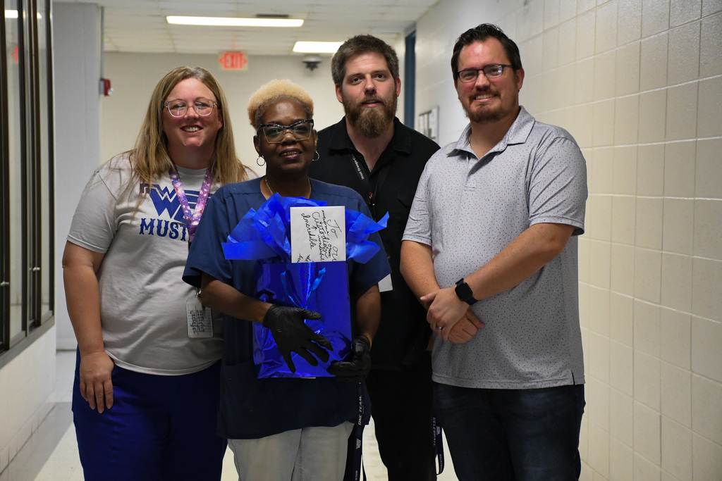 Teachers at WOSHS presenting a gift basket to custodian