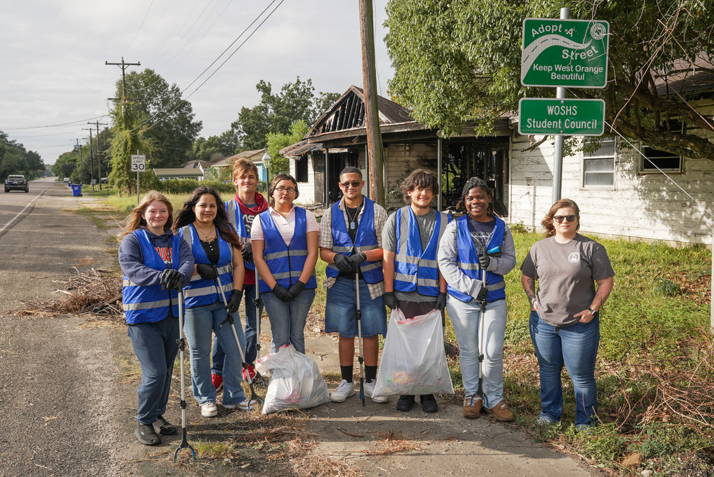 student council students and sponsor standing in front of the adopt a street sign