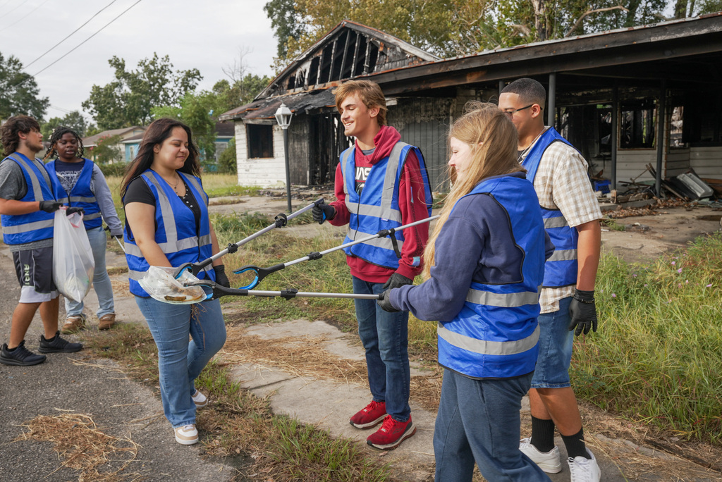 three students carrying a piece of trash together