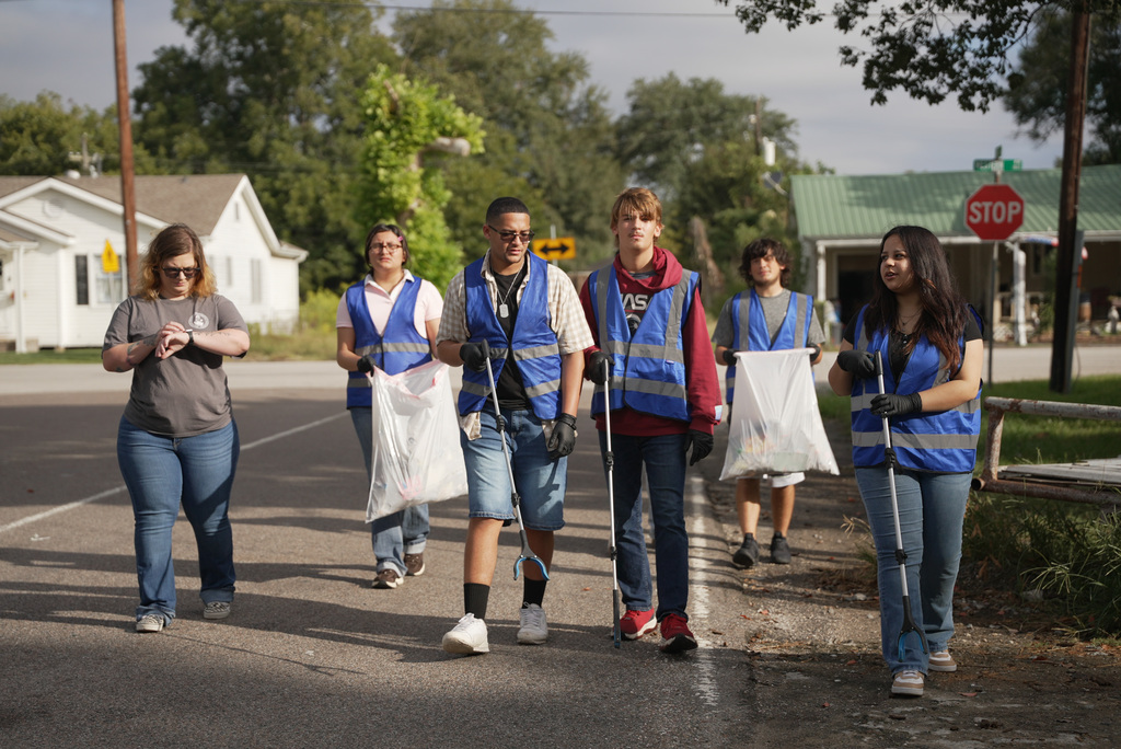 students walking along the street in a group looking for trash to pick up