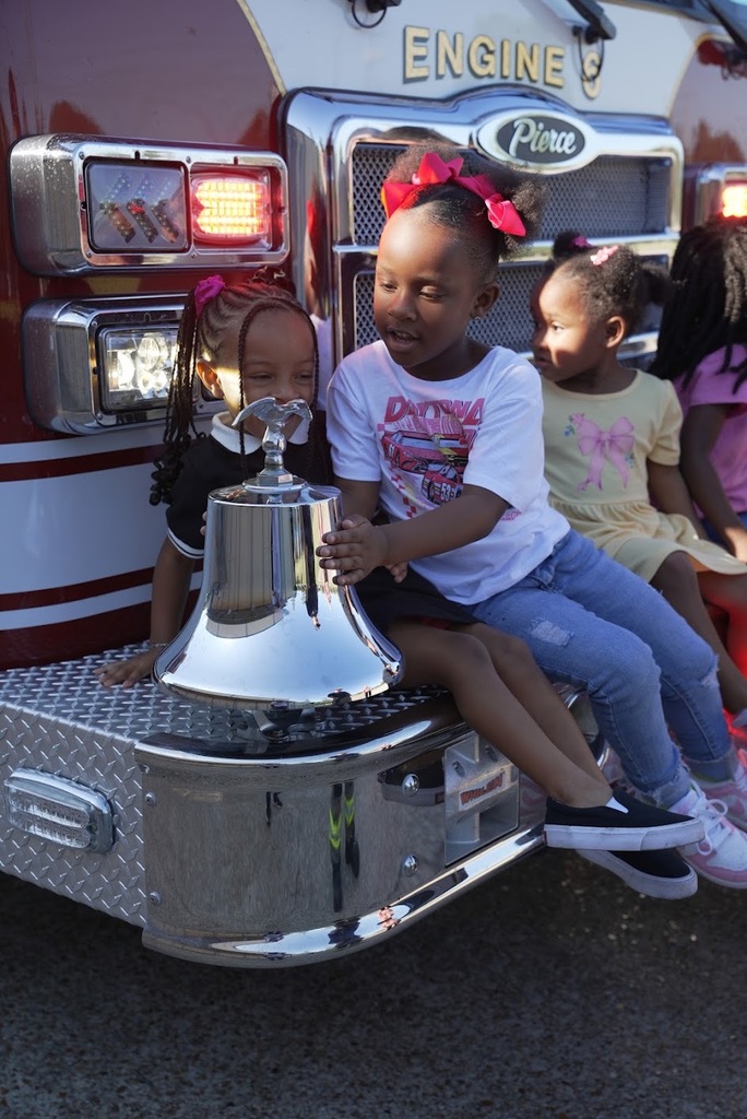 two girls playing with the bell on the front of fire truck
