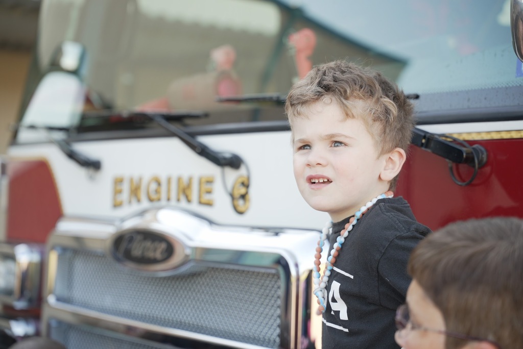 a boy looking away with a blurry Engine No 6 Fire truck in the background