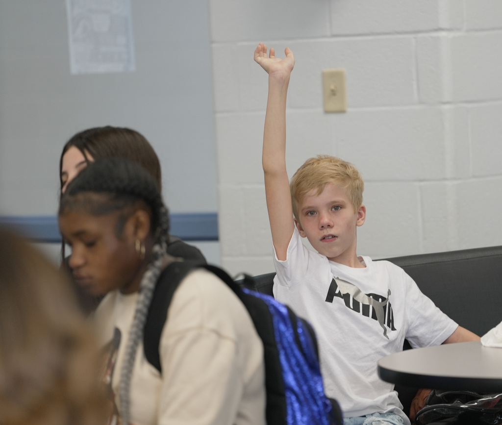 a boy raising his hand high in the air