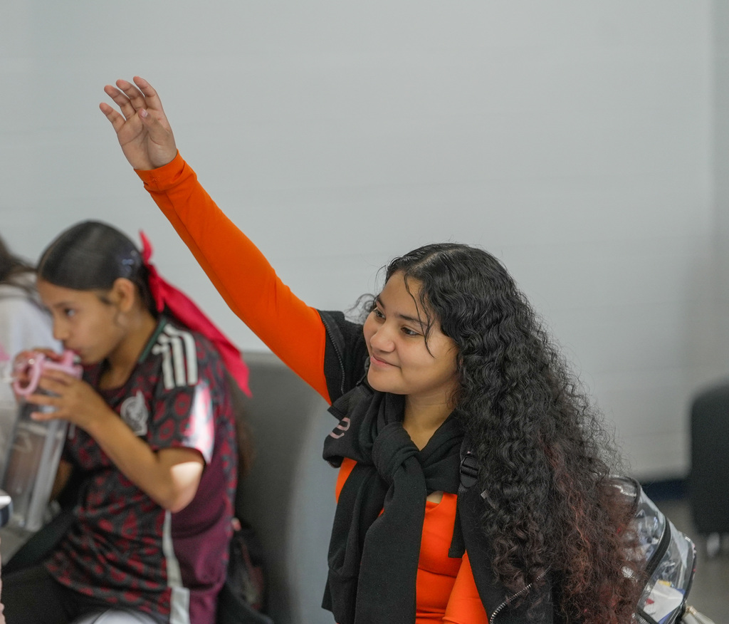 student smiling and raising her hand