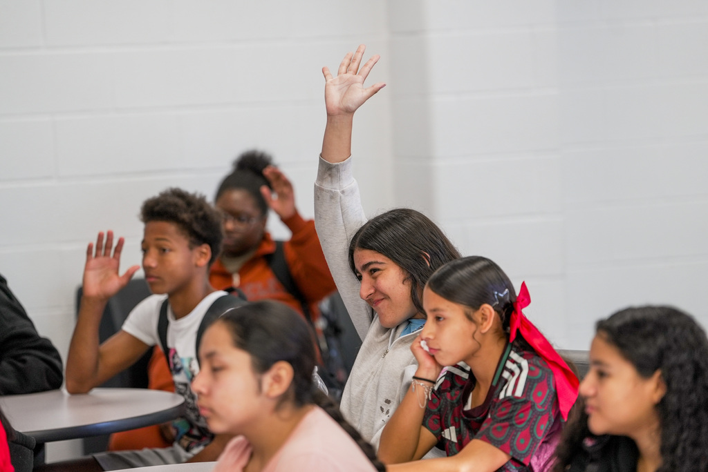 students raising their hand, one girl excitedly raises her above the others