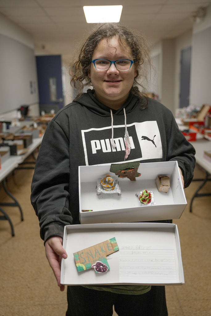 Student holding up a shoebox display for snake handler