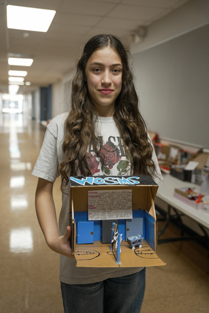 student holding up a shoebox display of a volleyball court