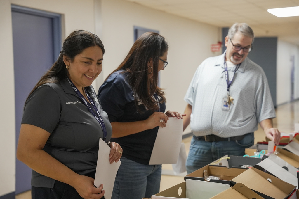 3 staff judges smiling while reviewing student projects.