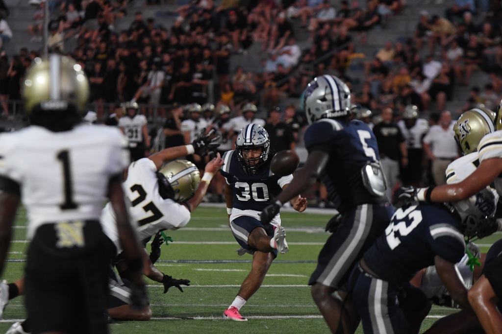 #30 kicking for the extra point after a touchdown, an opposing player tries to block unsucsseusfully