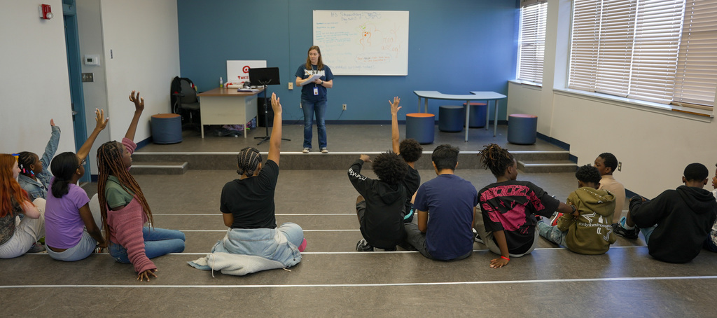Students raising hand as teacher writes their names down