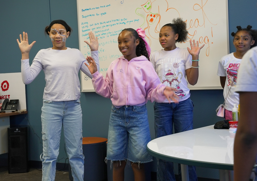 students performing a play, 3 girls holding their hands up